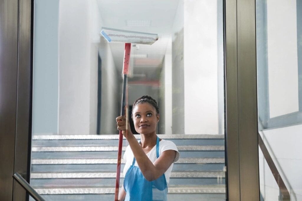 Woman cleaning glass door with squeegee